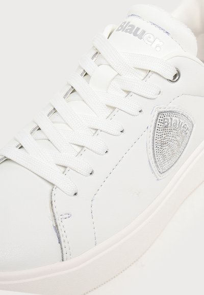 White sneaker with white laces, silver Blauer logo on the tongue, and a silver rhinestone shield emblem on the side.