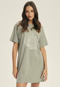 Jasnozielona sukienka w kształcie T-shirtu z miękkiego materiału, z krótkimi rękawami i białym graficznym wzorem liścia z przodu.
