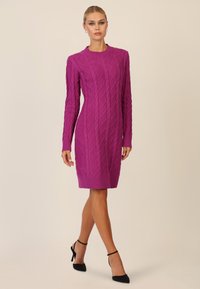 Aansluitende geribbelde gebreide jurk in levendig magenta, met een gestructureerd ruitpatroon, lange mouwen en een ronde halslijn.