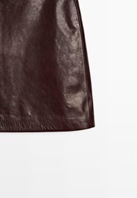 Burgunderrote Lederrock mit glatter Textur, geradem Schnitt und subtiler Schimmer, mit sauberen Kanten und ohne sichtbare Verschlüsse oder Akzente.