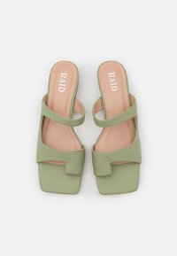 Sandali slide in ecopelle verde con punta quadrata, due cinturini regolabili e un design con aperture. Soletta imbottita color tan con logo del marchio.