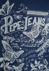 Námořnická modrá tkanina s bílým potištěným textem a grafikou motýlů. Obsahuje dekorativní ozdoby a rozptýlené jemné ozdoby.