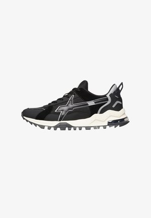 Zwarte sportieve schoenen met een mix van mesh en suède materialen, een dikke witte zool en een opvallend zilveren logo aan de zijkant.
