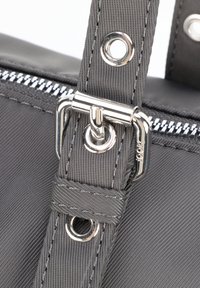 Szara torba z tkaniny o teksturowanym wykończeniu; posiada srebrny zamek błyskawiczny oraz metalowe dodatki, w tym klips i oczka.