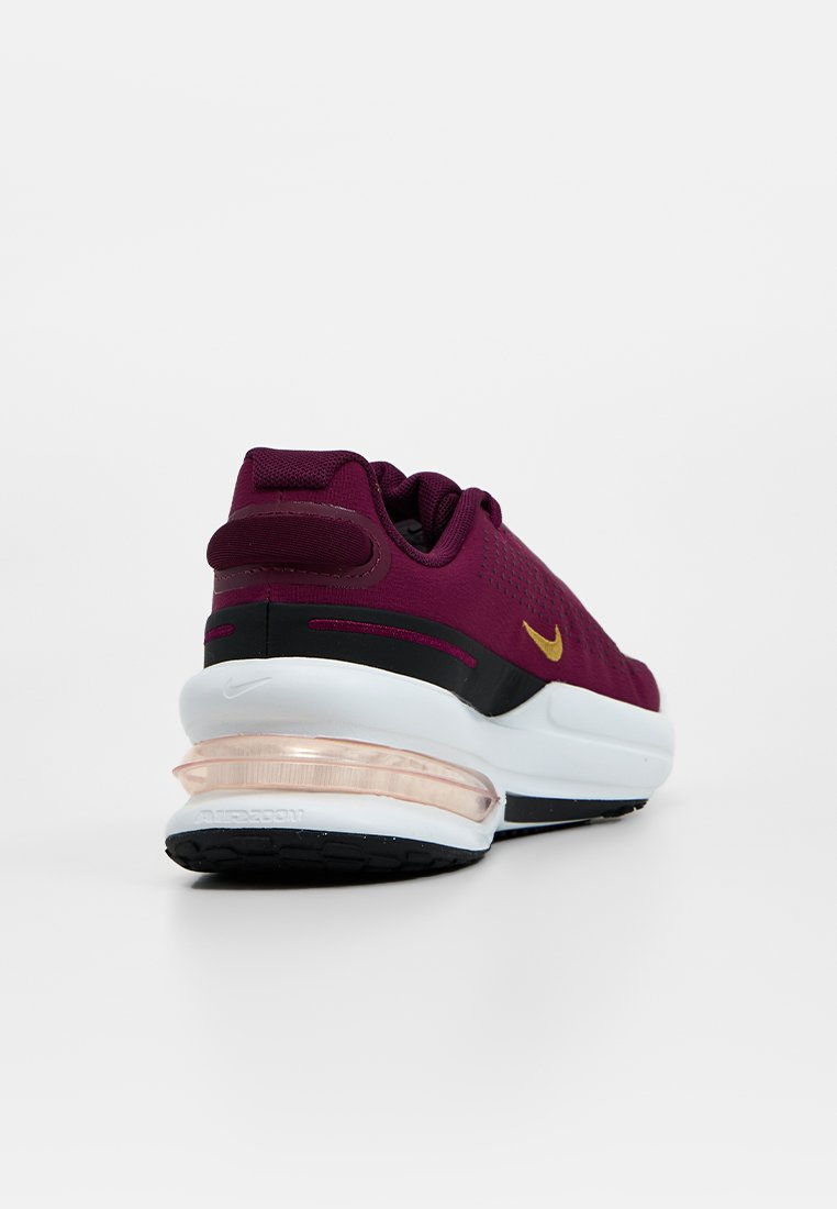 Zapatilla de running Nike en malla burdeos oscuro con un logo dorado, base en blanco y negro y un detalle de aire acolchado transparente en el talón.