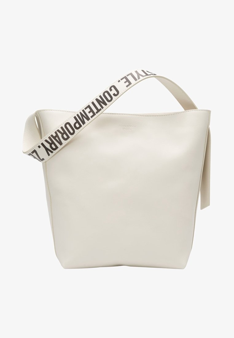 Sac cabas en cuir blanc avec une large bandoulière en tissu portant un texte noir indiquant "CONTEMPORARY STYLE."