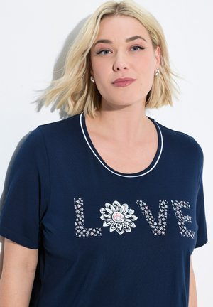 Camiseta azul marino de manga corta, con la palabra "LOVE" en un diseño floral y un motivo central de margarita. Tiene un escote blanco contrastante.