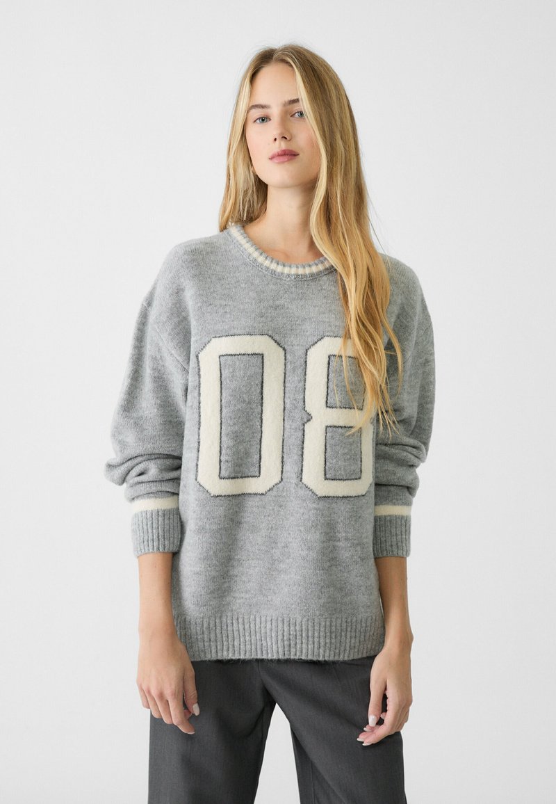 Grauer gestrickter Pullover mit der Zahl "08" in Creme. Mit gerippten Bündchen und Saum, rundem Halsausschnitt und einer weichen Textur.