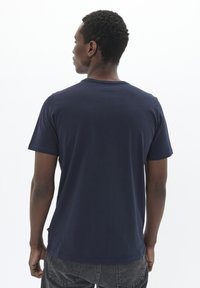 Camiseta de algodón azul marino con cuello redondo y mangas cortas, que presenta una textura suave y un ajuste estándar. La vista trasera no muestra logotipos visibles.