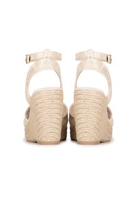 Sandalias de cuña con tacón de yute trenzado, parte superior sintética en suave tono beige, correa en el tobillo con hebilla y diseño abierto en la parte trasera.