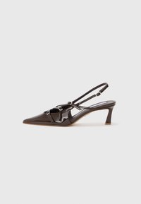 Tacco slingback in pelle verniciata marrone con punta affusolata, cinturini regolabili e fibbie decorative sul davanti. Altezza del tacco di 3 pollici.