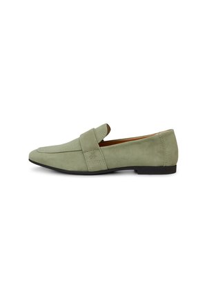 Mocassin en daim vert clair avec semelle noire, talon plat, et une lanière traversant le dessus, présenté en profil latéral sur fond blanc.
