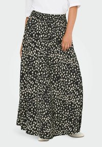 Gonna maxi nera con macchie astratte crema, dotata di una vita elastica e tessuto fluente, abbinata a una maglietta bianca semplice e calzature leggere.