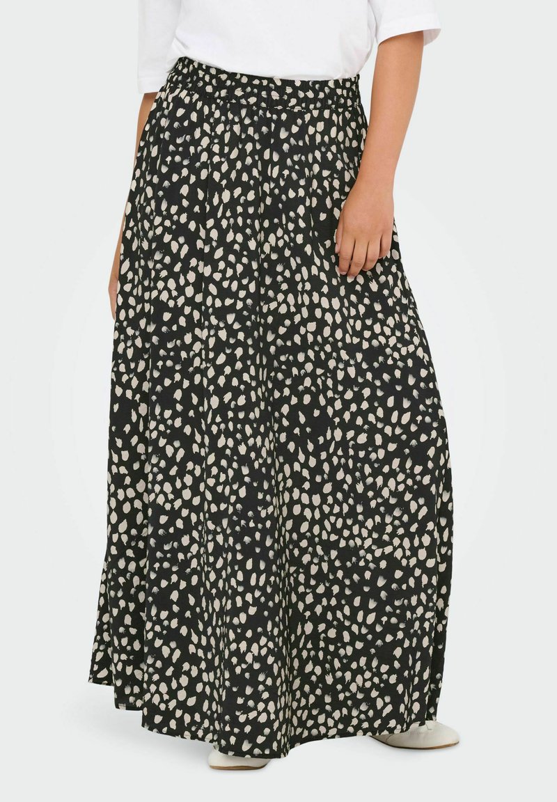 Gonna maxi nera con macchie astratte crema, dotata di una vita elastica e tessuto fluente, abbinata a una maglietta bianca semplice e calzature leggere.