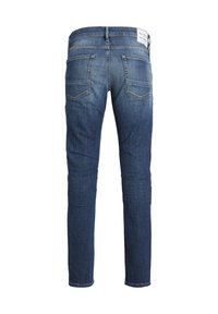 Vaqueros de denim azul oscuro con un corte ajustado, cinco bolsillos y un ligero desgaste. Presenta una etiqueta de marca en la cinturilla.