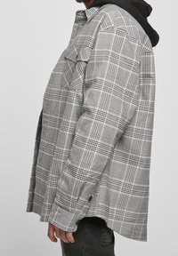 Gråternet flannel skjorte med sorte accenter, der har to frontlommer, knapmanchetter, en afslappet pasform og en lidt længere bagkant.