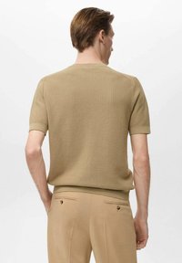 Beige pletený svetr s krátkým rukávem a strukturovaným povrchem. Kulatý výstřih a žebrované manžety doplňují přiléhavý design.