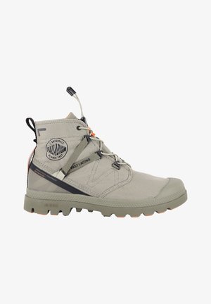 Bota impermeable alta de color beige con sistema de atado rápido, suela resistente y logo de Palladium en el lateral, diseñada para uso urbano.
