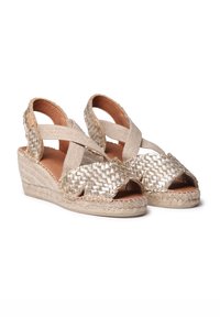 Kudottu kultainen espadrille-sandaali, avoimella varvashuolella, teksturoidusta metallista valmistettu päällinen ja juuttikankaasta kiedottu korokkeellinen kantapää. Säädettävä ristikkäin nauha.