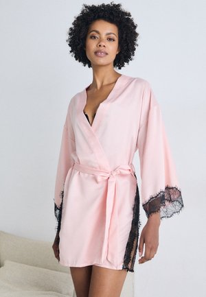Accappatoio in satin rosa chiaro con accenti in pizzo nero sulle maniche e ai lati, con design avvolgente e una cintura in vita per la chiusura.