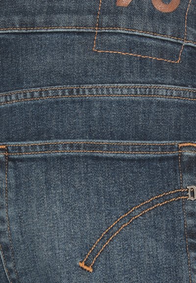 Jeans de mezclilla con un lavado azul oscuro, con costuras naranjas, bolsillos traseros y una etiqueta de cuero con el número '70'.