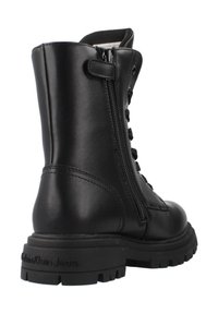 Stivale alla caviglia in pelle nera con punta rotonda, lacci anteriori, chiusura con zip laterale e suola in gomma resistente. Marchio Calvin Klein Jeans sul tallone.