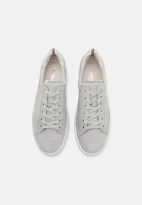 Baskets en daim gris à coupe basse, avec des lacets plats, une semelle en caoutchouc blanche, et un subtil accent métallique au talon.