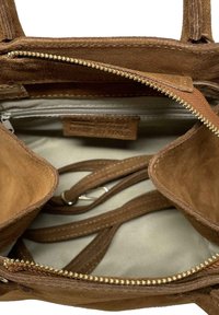 Borsa in suede marrone con un ampio interno. Presenta un scomparto con zip e tasche aggiuntive, completata da manici in pelle e accessori in oro.