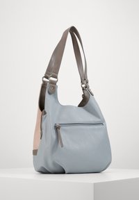 Sac en cuir bleu clair avec accents gris, une seule sangle, et une poche avant zippée ; forme arrondie avec une texture lisse et des couleurs contrastées.