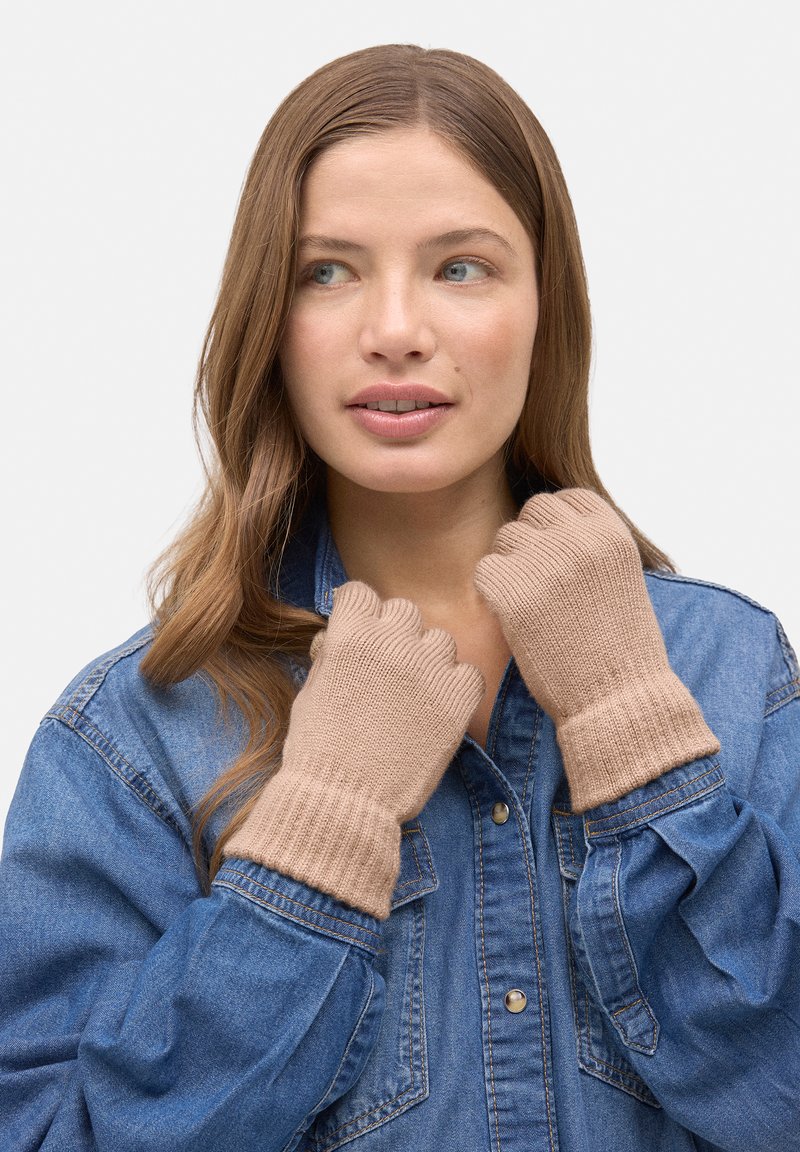 Guantes sin dedos de punto color marrón claro con puños acanalados, usados por una persona con camisa de mezclilla. Textura suave, diseño sencillo, sin patrones adicionales.