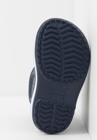 Semelle de chaussure en caoutchouc bleu marine avec un motif de tread texturé et une garniture blanche. Présente un logo et un marquage de taille en relief au bas.