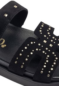 Sandali in suede neri con accenti in borchie. Presentano larghe cinghie e una suola imbottita, evidenziando dettagli in hardware dorato a contrasto.