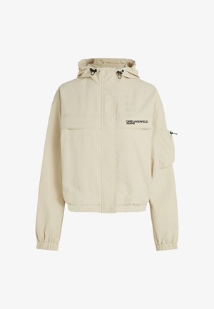 Beige színű, kapucnis, rövid dzseki, rugalmas mandzsettákkal és cipzáros elülső résszel. Logónyomattal és több zsebbel rendelkezik, könnyű anyagból készült.