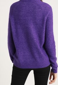 Lila, übergroßer Strickpullover mit rundem Halsausschnitt, gerippten Bündchen und Saum. Weicher Stoff, Raglanärmel und lockere Passform.