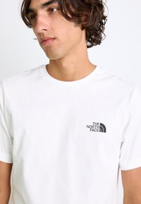 Hvid bomulds T-shirt med rund halsudskæring og korte ærmer. Bemærkelsesværdig sort logo fra The North Face på brystet.