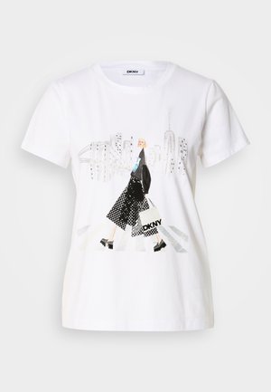 Maglietta bianca in cotone con un'illustrazione colorata di una figura con gonna nera a pois e scarpe con zeppa nere, sullo sfondo lo skyline di una città.