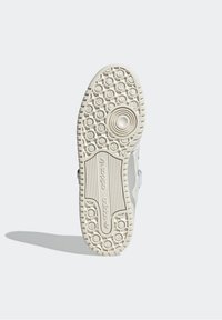 White rubber sneaker sole with textured grip patterns, featuring a circular logo and embossed brand name along the midsole.