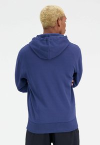 Marineblauwe hoodie met een relaxte pasvorm, voorzien van een trekkoordcapuchon en ribgebreide manchetten. Zacht stof met een gladde textuur, zonder zichtbare patronen.