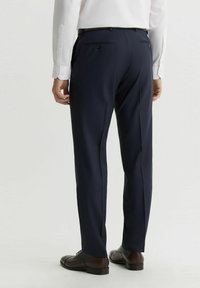 Granatowe spodnie wizytowe wykonane z gładkiego materiału, z dwiema tylnymi kieszeniami, szlufkami na pasek oraz dopasowanym krojem z zakładką z przodu.