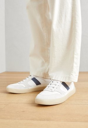 Sneakers bianchi con dettagli in suede e rete, caratterizzati da una striscia blu navy. Hanno una punta rotonda e una suola in gomma testurizzata.