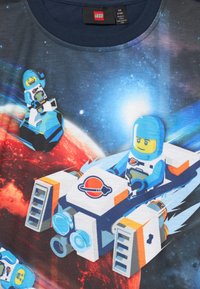 Koszulka dziecięca z LEGO astronautami i statkami kosmicznymi przelatującymi nad czerwoną planetą na tle gwiaździstego nieba.