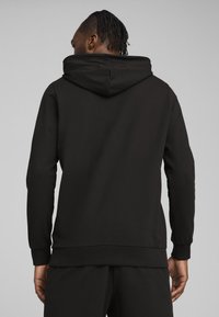 Sort hættetrøje med en stor baghætte, ribbede manchetter og kant. Glat stof med minimale sømme, designet til en afslappet pasform.