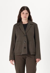 Brun patterned jakke med notches krage, tre store knapper og lange ermer. Stoffet har en teksturert utseende med flerfargede detaljer.
