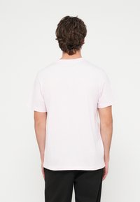 Ροζ βαμβακερό μπλουζάκι με στρογγυλή λαιμόκοψη και κοντά μανίκια, με απλό σχέδιο χωρίς ορατά μοτίβα ή διακοσμητικά στοιχεία.