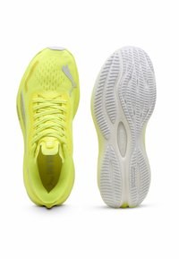 Scarpe da allenamento giallo brillante con una tomaia in mesh testurizzato, chiusura con lacci e una suola in gomma bianca con un motivo di battistrada ondulato.