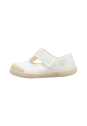 Zapato blanco para niño pequeño con suela de goma beige y correa ajustable de velcro en la parte superior, mostrado sobre un fondo blanco.