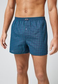 Boxershorts in een donkerblauw en groen ruitpatroon. Gemaakt van lichtgewicht stof, met een elastische tailleband en een bevestigingsknop aan de voorkant.