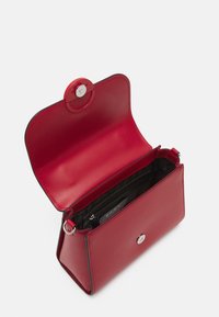 Sac à main en cuir rouge avec une finition texturée, doté d'une fermeture à pression magnétique, d'une poche intérieure et d'accents de matériel argenté.