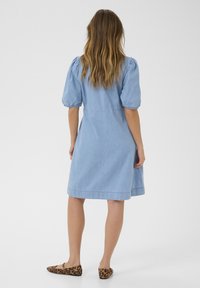 Kék farmerruha puff ujjakkal, térd hosszúságú szabással és laza fit. Leopárdmintás slip-on cipővel párosítva.