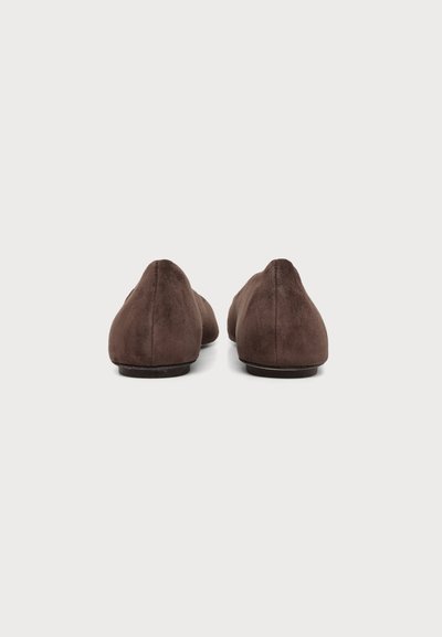 Paire de chaussures plates en daim marron vues de dos sur fond blanc uni avec des talons bas et arrondis.